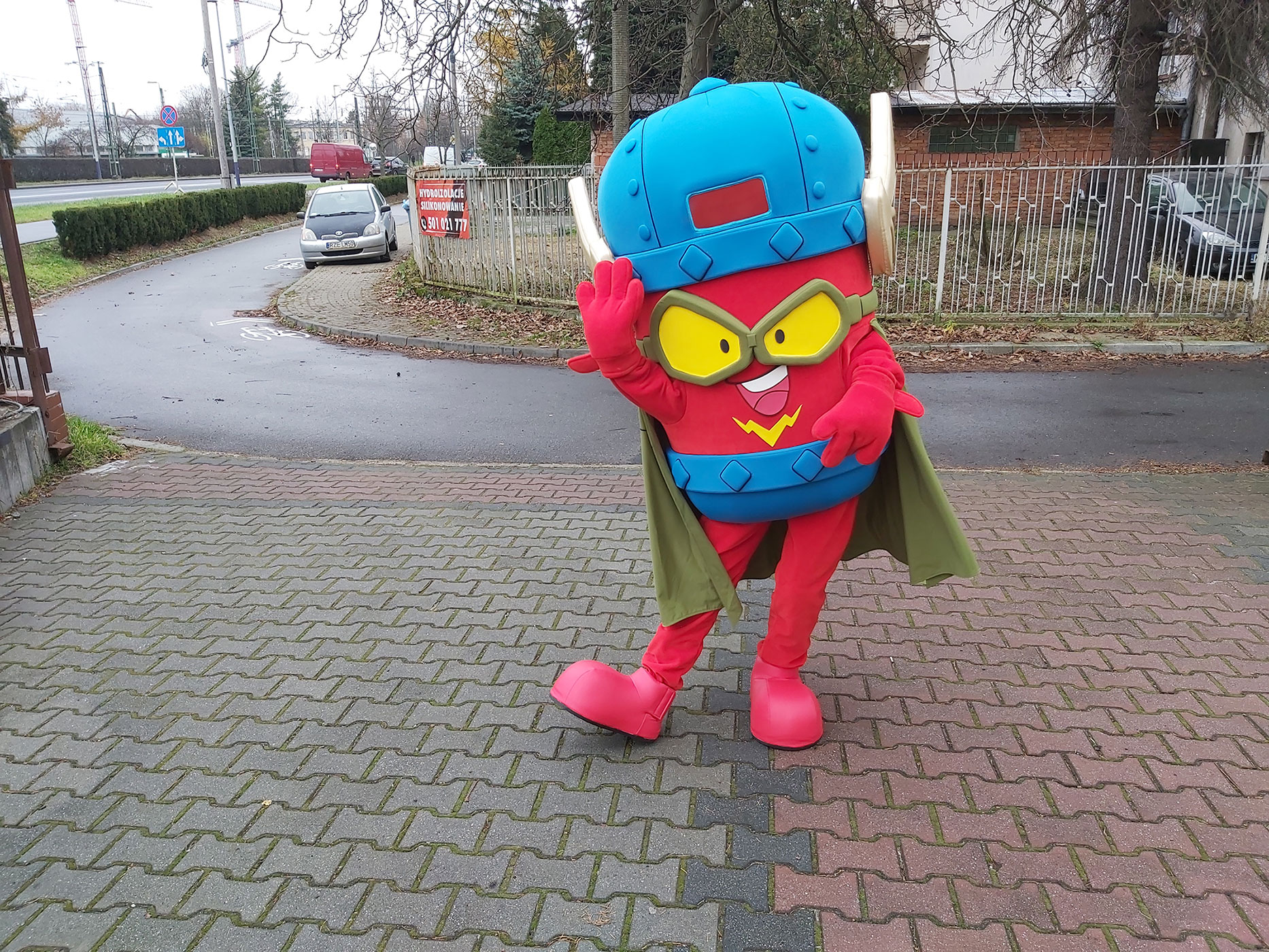 N fotografii widnieje przebranie za figurkę SuperZings Kid Fury pozujące do zdjęcia przed siedzibą firmy Elabika